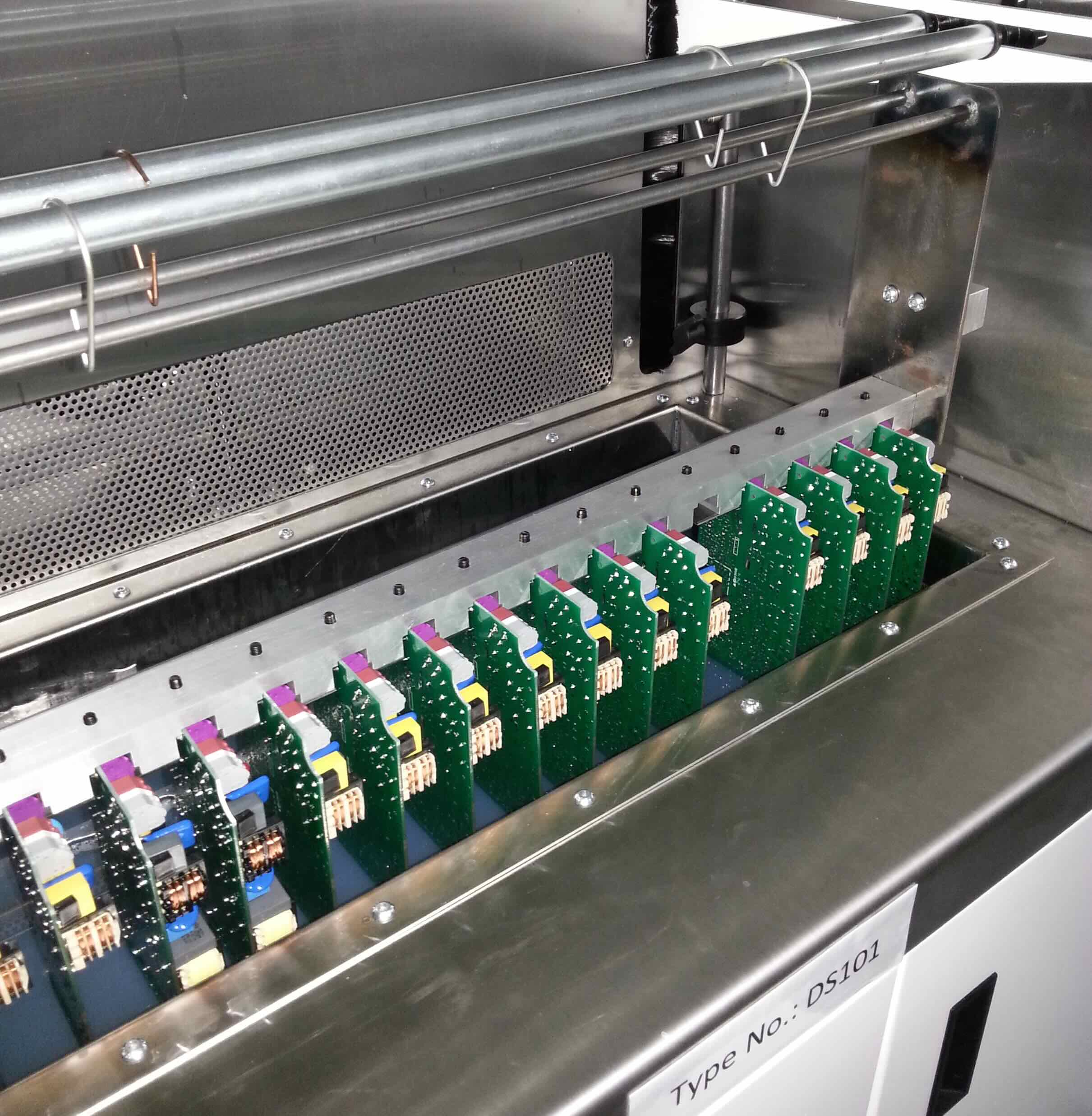PCB being dip coated in conformal coating bath showing controlled withdrawal and drainage
